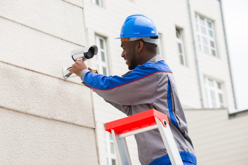 Technician installing security camera outside building